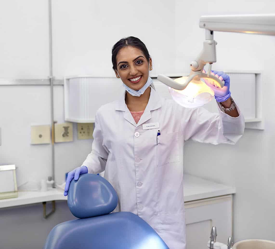 Portrait of a young female dentist standing alongside the dental chair in her office.